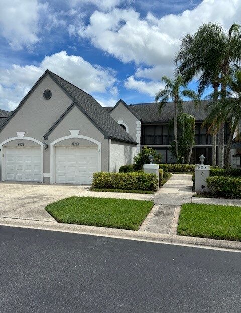 Modern two-story house with a double garage and palm trees.