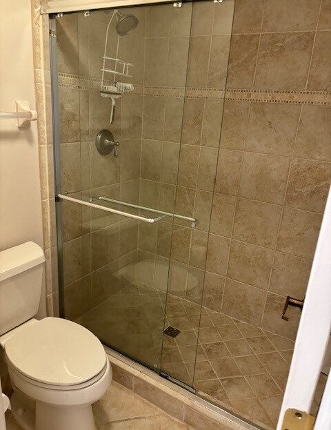 Small bathroom with glass shower door and beige tiles.