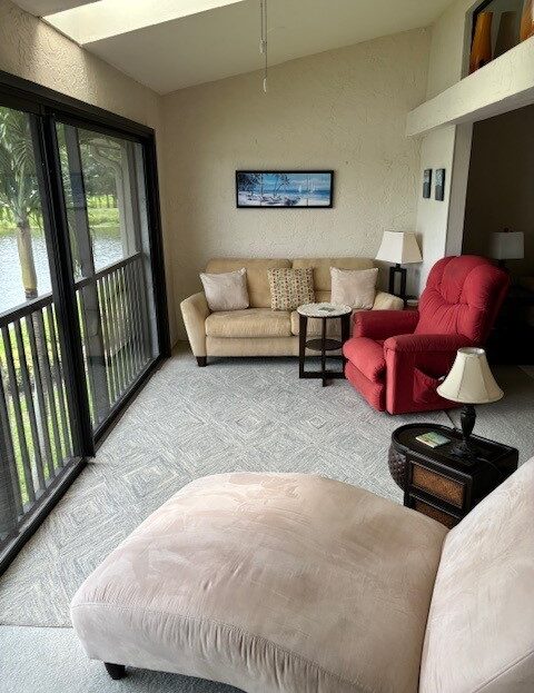 Cozy living room with beige sofa and red armchair by large windows.