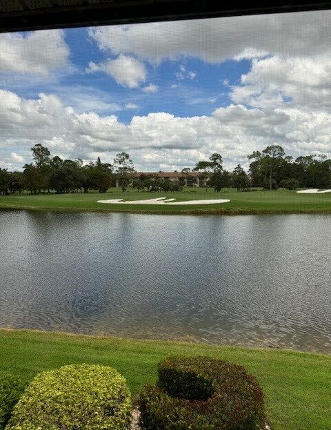 Scenic golf course with pond and blue sky.