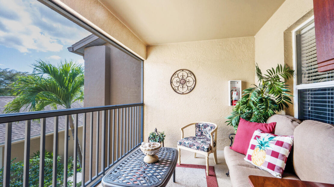 Cozy outdoor balcony with comfortable seating and decorative plants.