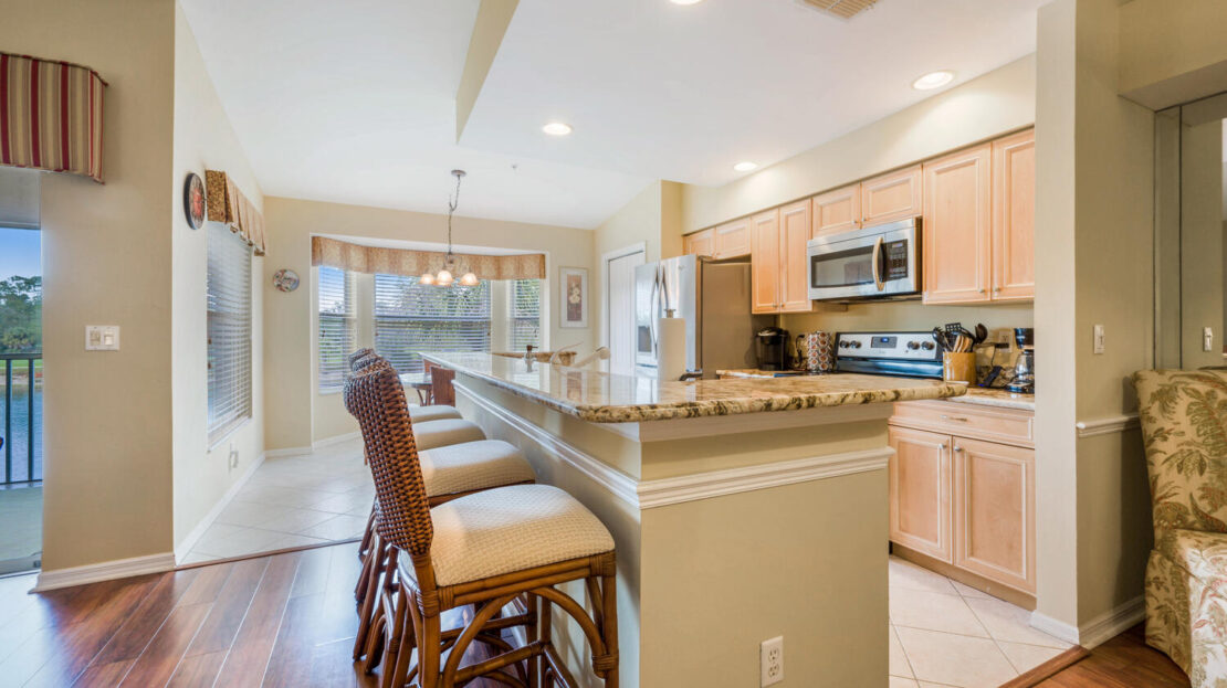Modern kitchen with bar stools and granite countertops.