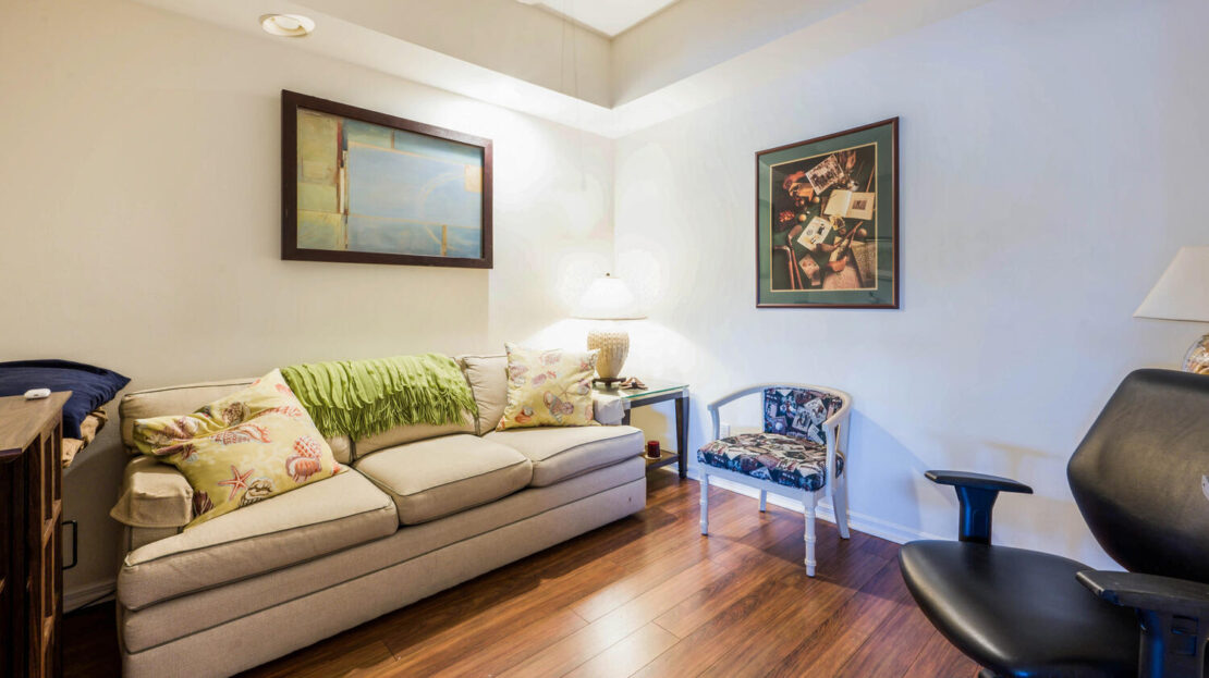 Cozy living room with sofa, chair, and framed artwork on walls.