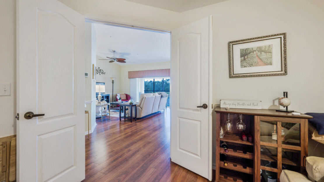 Open double doors reveal a bright, spacious room with wooden floors.