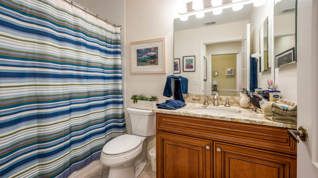 Cozy bathroom with wooden vanity and striped shower curtain.