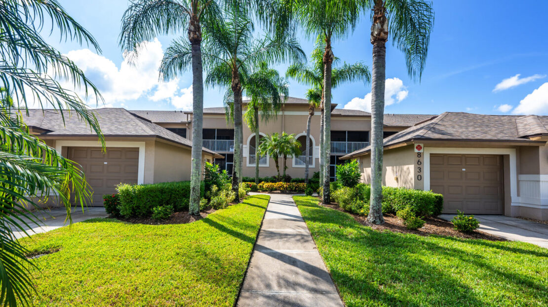 Modern two-story house with palm trees and a concrete walkway.