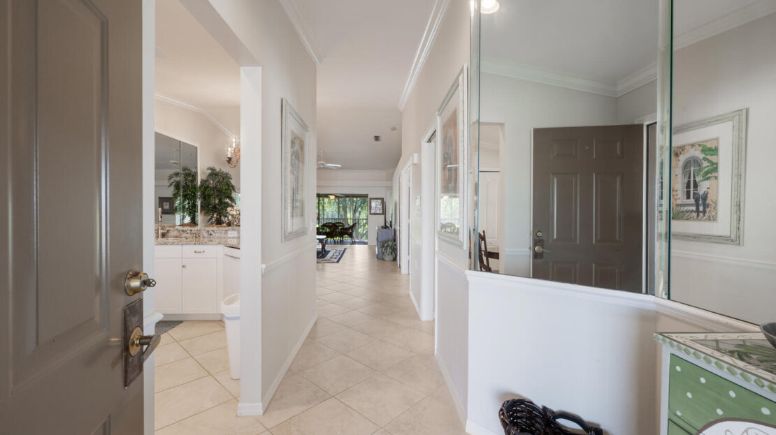 Bright hallway with white walls and beige tiled floor leading to a living area.