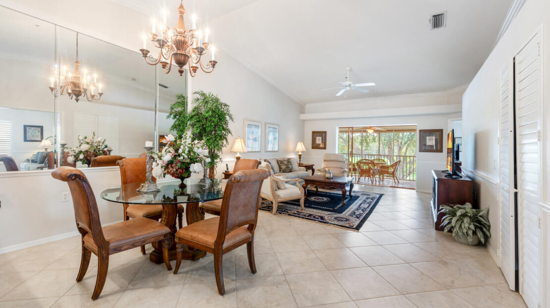 Elegant dining and living area with chandelier and large windows.