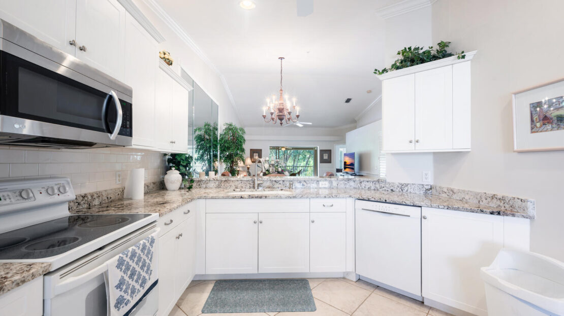 Bright, modern kitchen with white cabinets and chandelier.