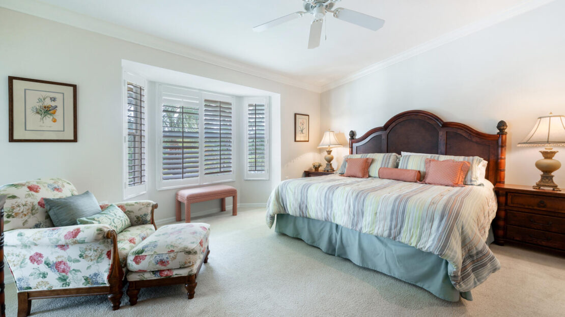 Bright bedroom with a large bed and floral armchair.