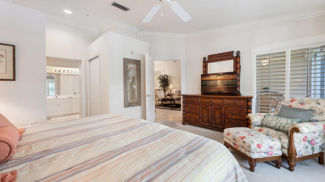Bright bedroom with striped bedding, ceiling fan, and vintage dresser.