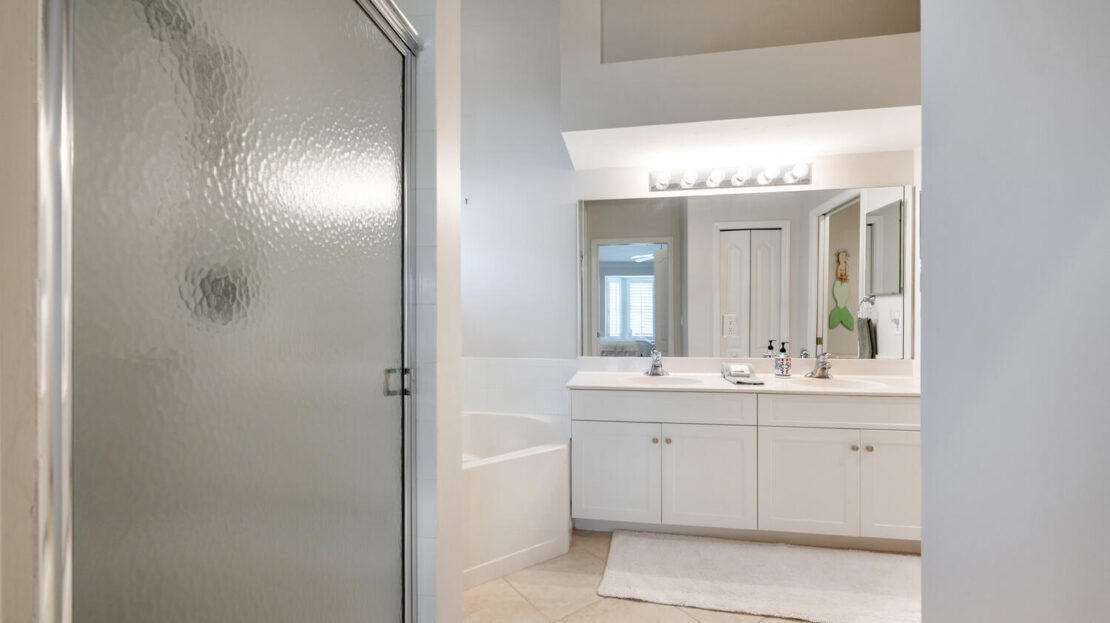 Bright, modern bathroom with white cabinetry and frosted glass shower door.