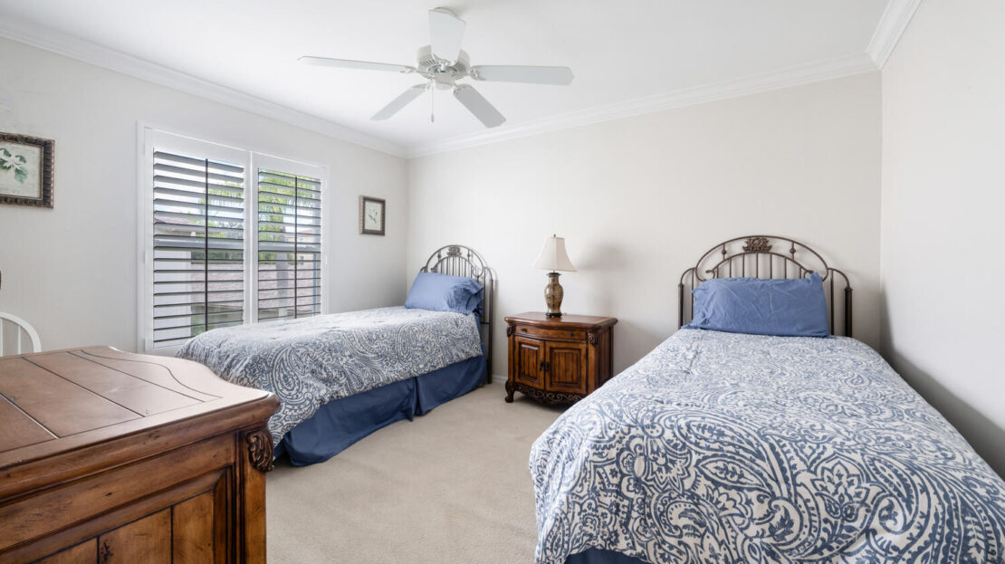 A bright bedroom with two twin beds and blue patterned bedding.