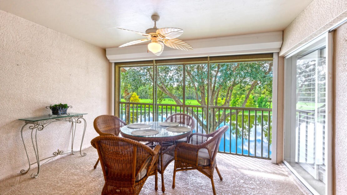 Cozy patio with wicker furniture overlooking a lush garden and pool.