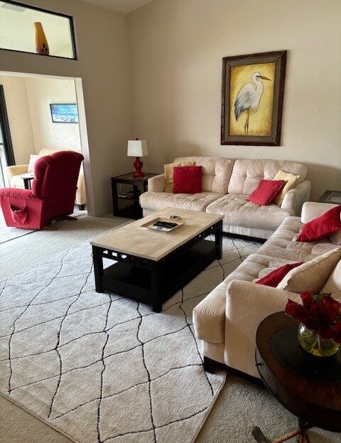 Cozy living room with beige sofas, red accents, and a wooden coffee table.