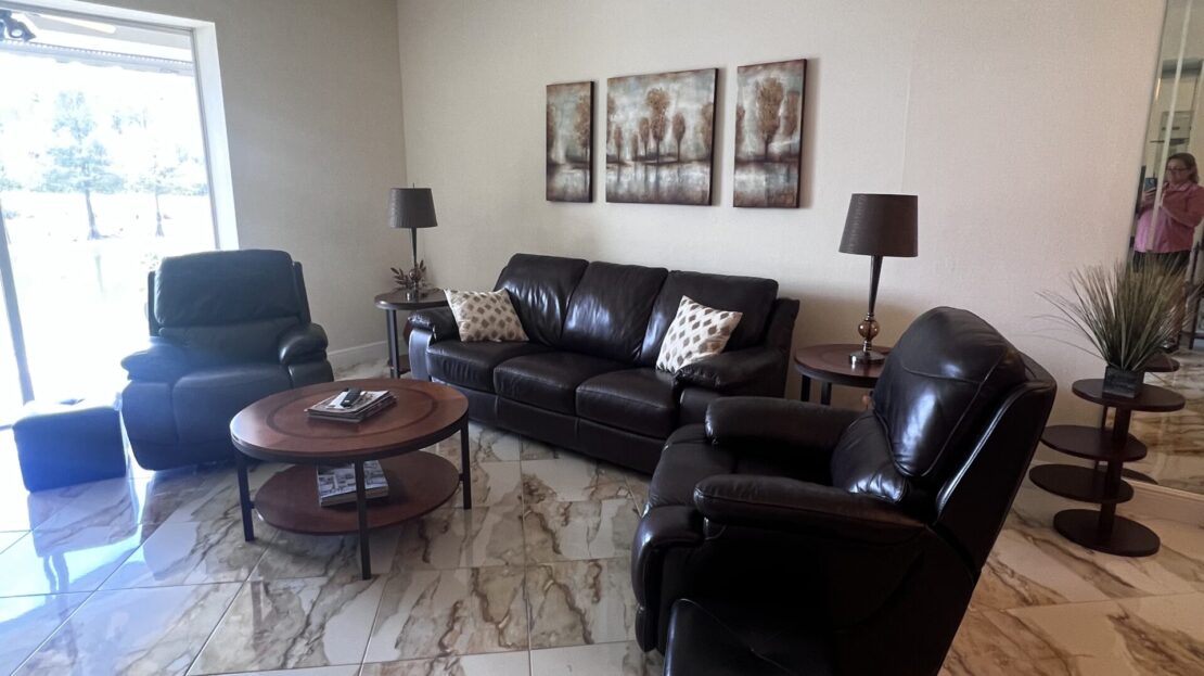 Modern living room with black leather furniture and marble flooring.