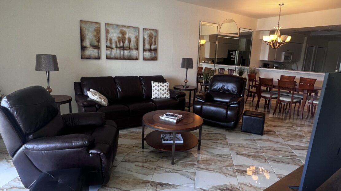 Cozy living room with dark leather furniture and marble flooring.