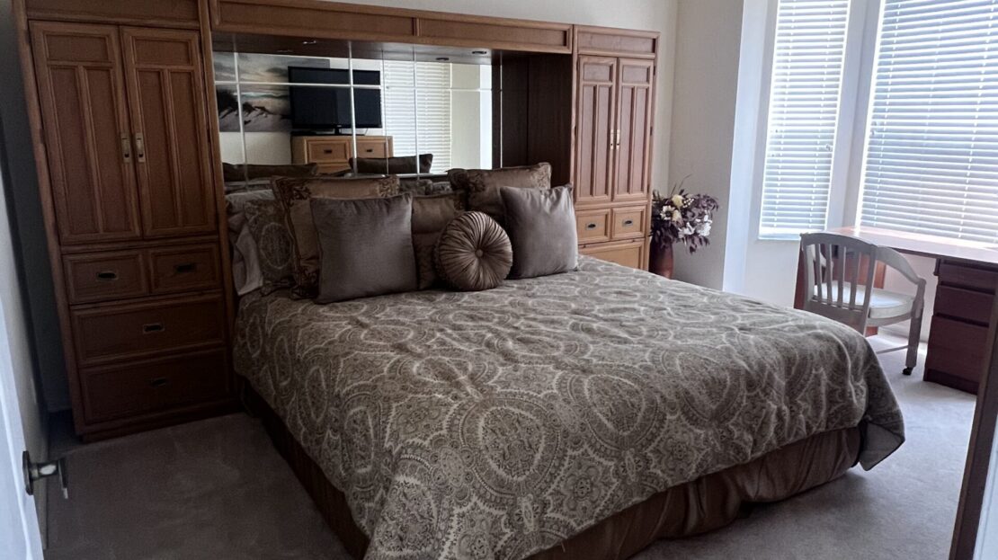 Cozy bedroom with a large bed, wooden furniture, and a bright window.