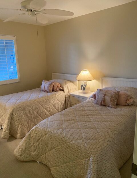 Cozy bedroom with two twin beds and a lit bedside lamp.