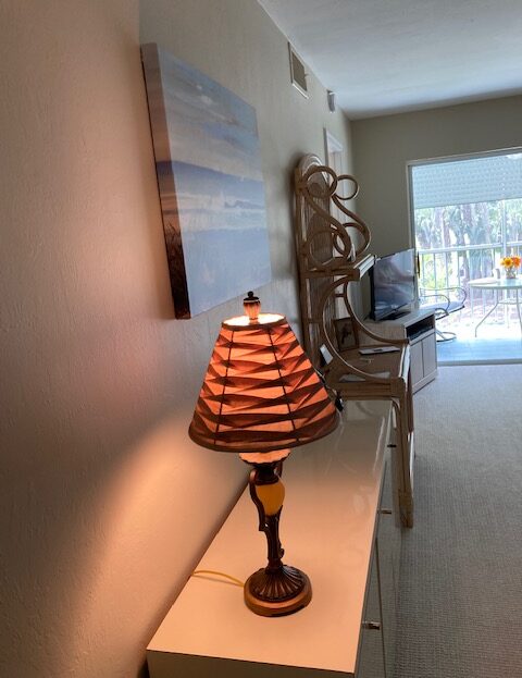 A decorative lamp with a striped shade on a table near a wall.