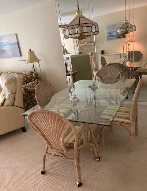 Glass dining table with wicker chairs in a cozy living room.