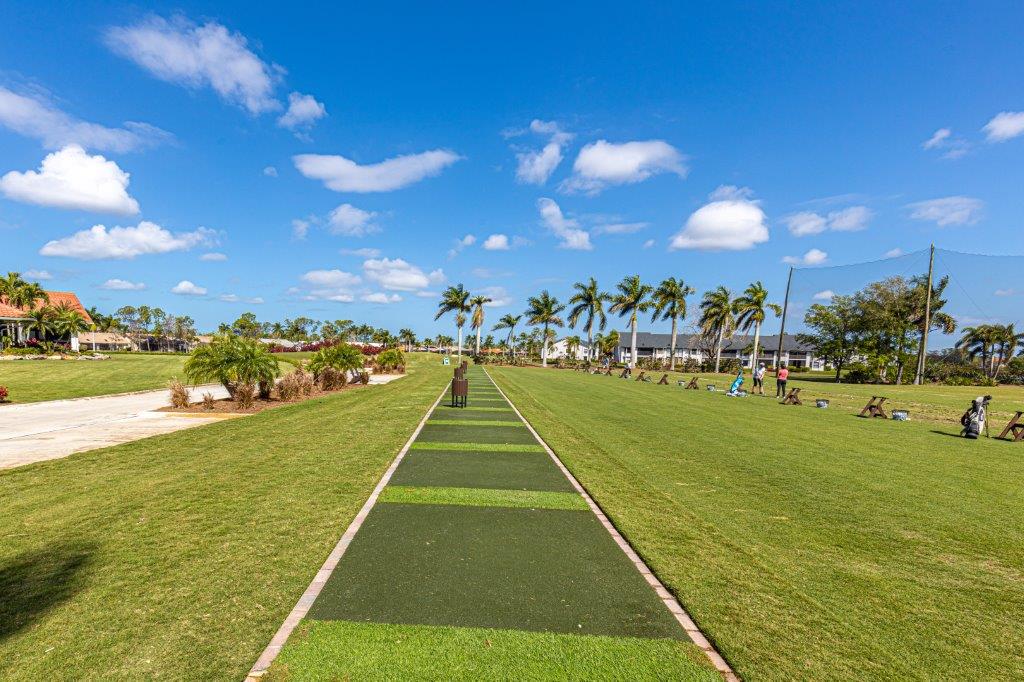 A long outdoor bocce ball court under a bright blue sky with scattered clouds.