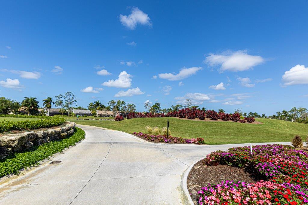A bright day with a curved road and colorful flowerbeds in a park.