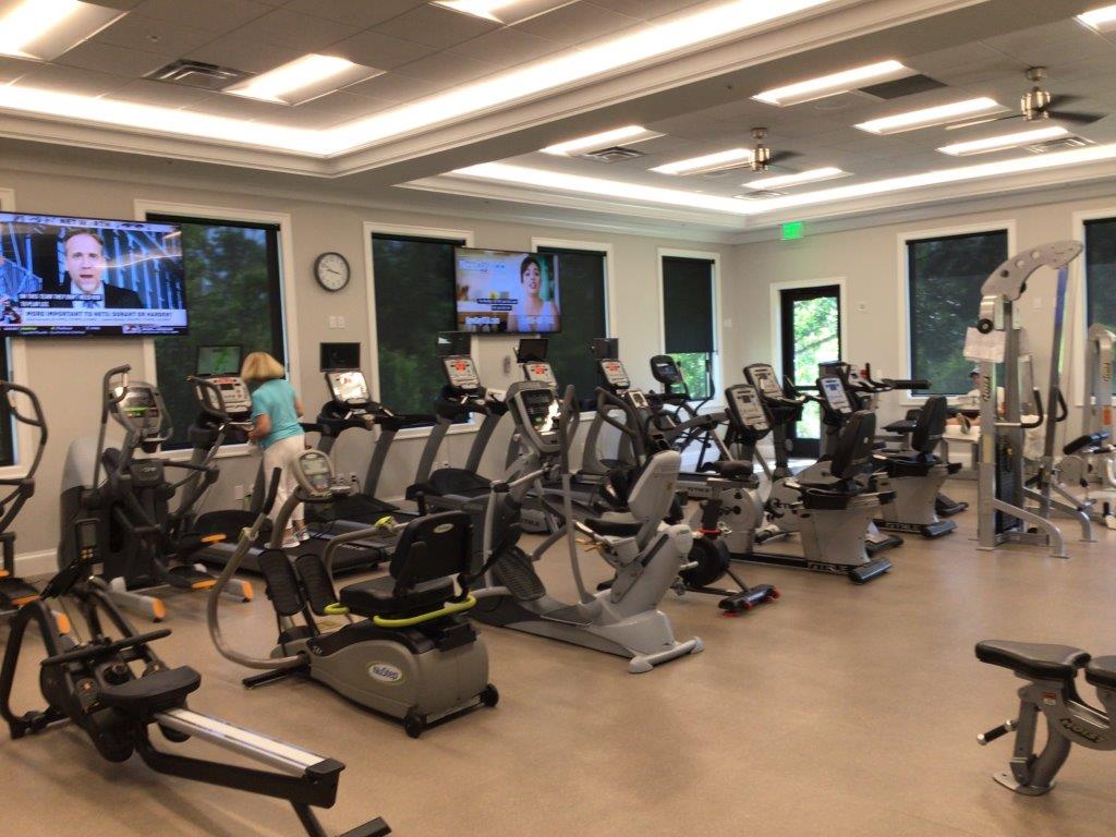 A spacious gym with cardio machines and large windows.