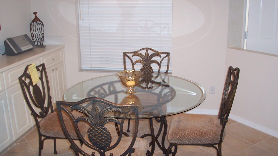Glass-top dining table with ornate metal chairs in a cozy room.