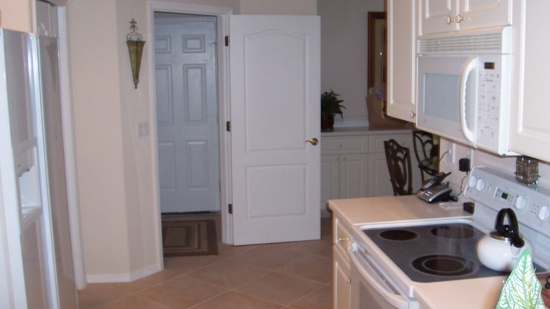 A compact kitchen with white cabinets and appliances.