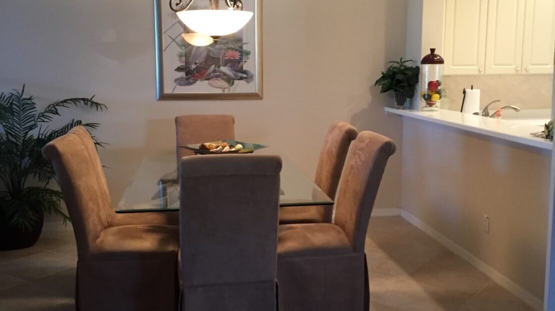 Elegant dining room with a glass table and four cushioned chairs.