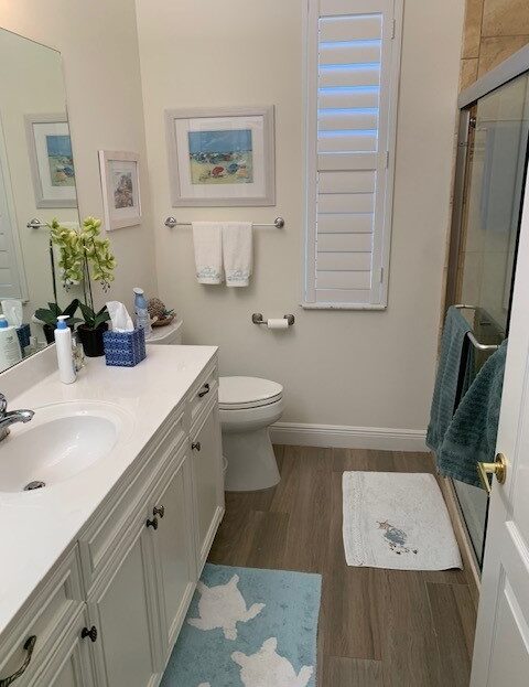 Clean and organized bathroom with white cabinetry and blue accents.