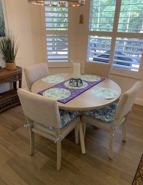 Cozy dining table with four cushioned chairs and a decorative table runner.