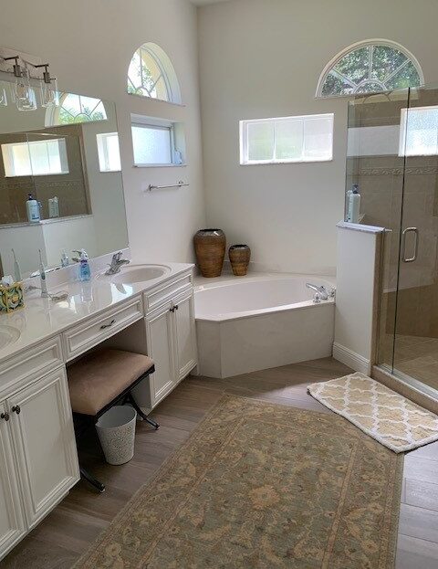 Bright bathroom with bathtub, glass shower, and double sinks.