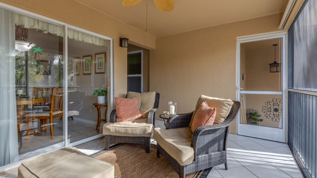 Cozy outdoor patio with cushioned chairs and a ceiling fan.