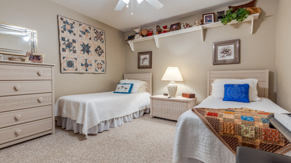 Cozy twin bedroom with quilted wall art and warm lighting.