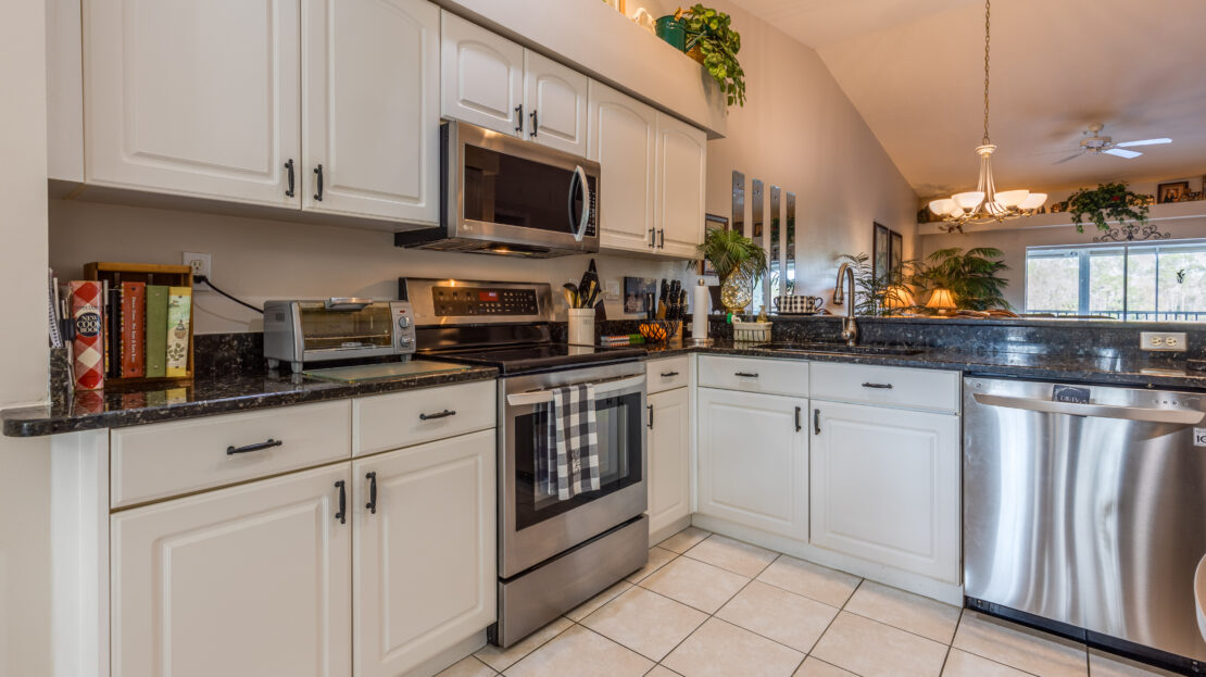 Modern kitchen with white cabinets and stainless steel appliances.