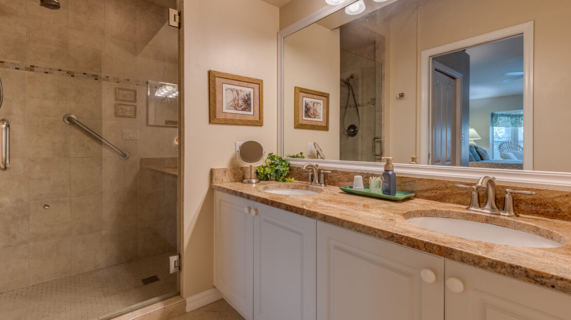 Modern bathroom with glass shower and granite countertop.