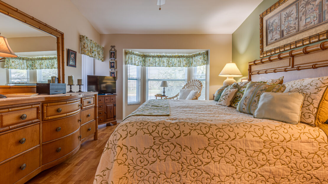 Cozy bedroom with patterned bedding and natural light from a large window.
