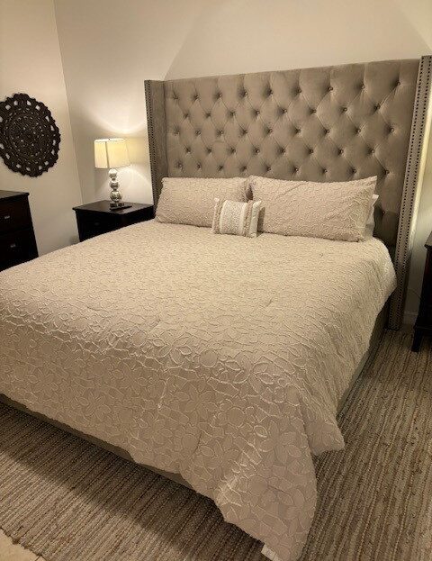 Cozy beige bedroom with a tufted headboard and matching bedding.
