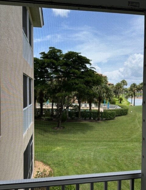 View from a building overlooking green grass, trees, and a partly cloudy sky.