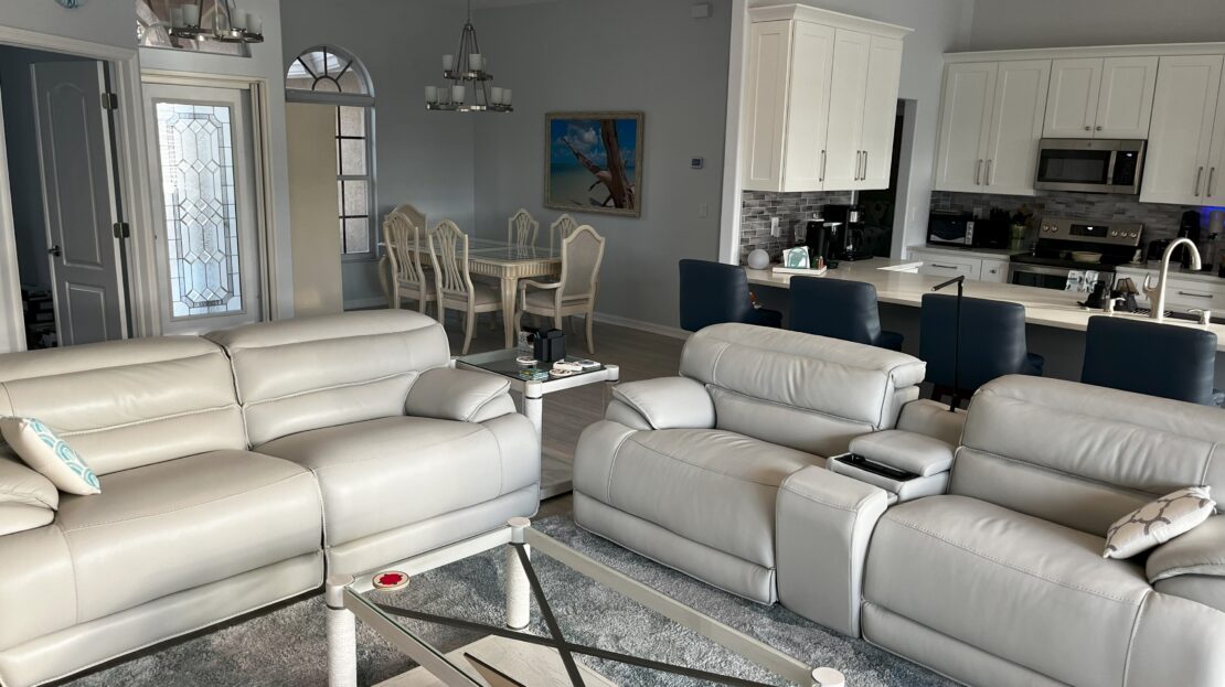 Modern living room with white leather sofas and glass coffee table.