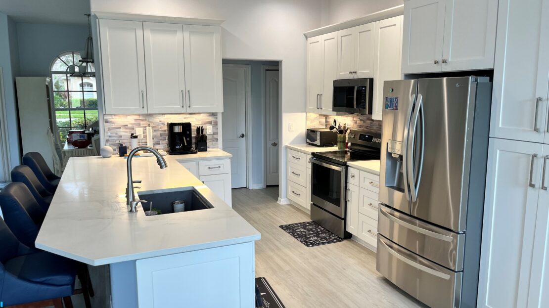 Modern kitchen with white cabinets and stainless steel appliances.