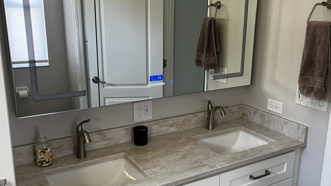 Modern bathroom vanity with white cabinets and marble countertop.