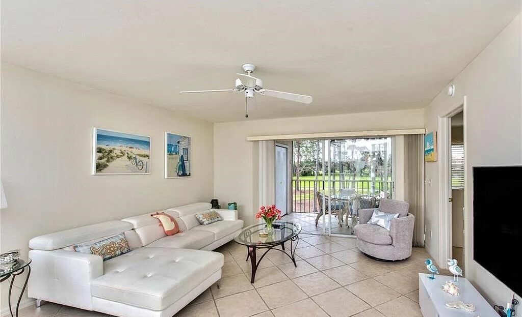 Bright living room with white furniture and sliding glass doors to a patio.