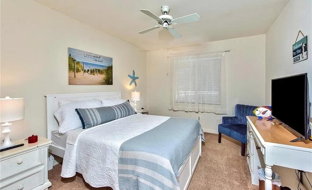 Cozy bedroom with blue and white decor and a ceiling fan.