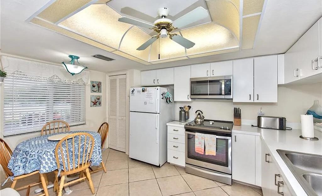 Bright and cozy kitchen with white cabinets and ceiling fan.