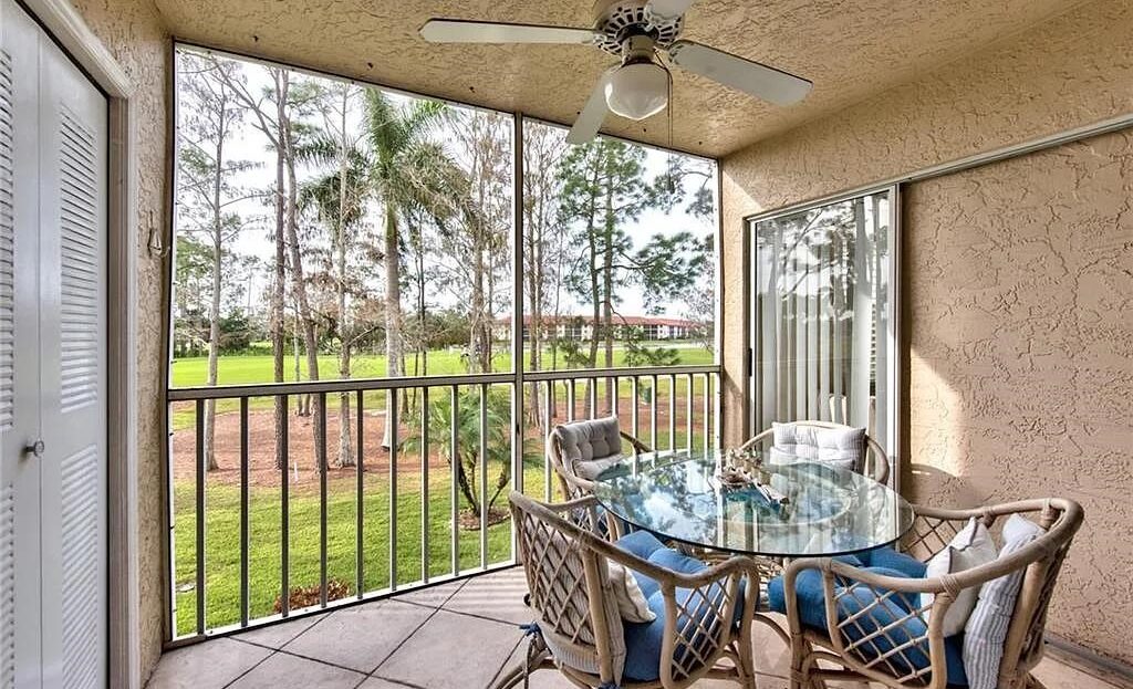 Cozy patio with glass table and chairs overlooking a green lawn and trees.