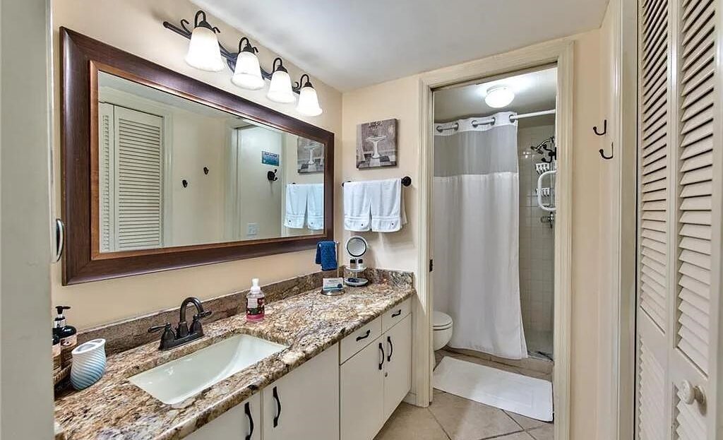 Clean bathroom with granite countertop and large mirror.