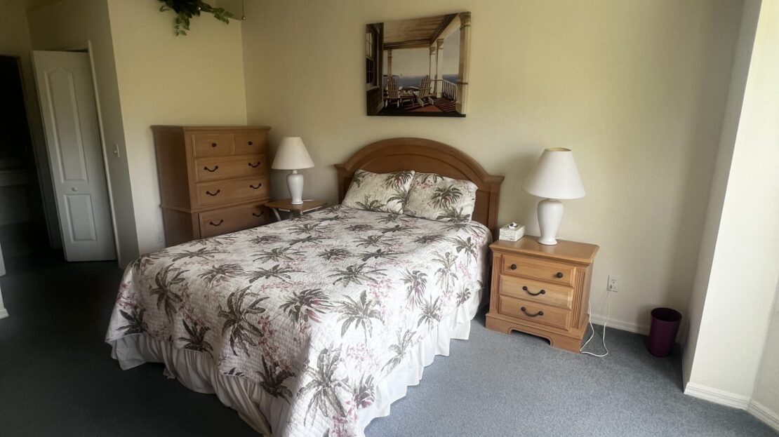 Cozy bedroom with floral bedspread and wooden furniture.